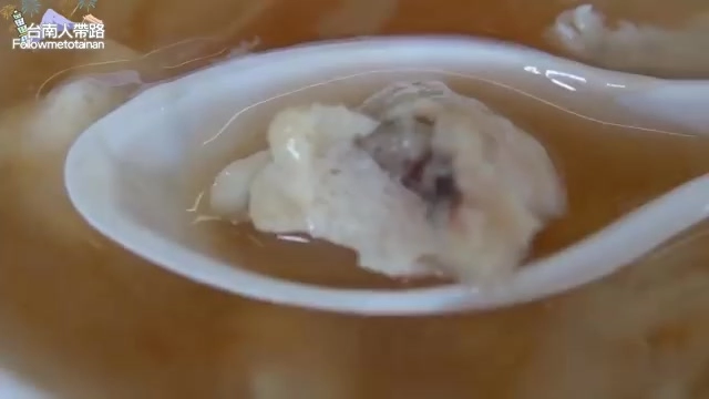 湯匙舀起魚羹料，可見魚漿包裹的餡料浸潤在湯汁中，質地細緻
