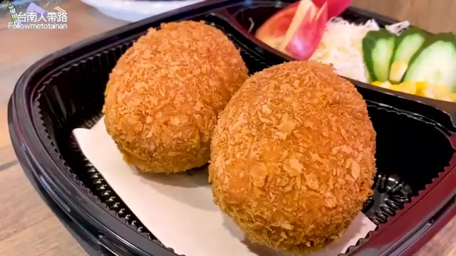 切開的蘇格蘭炸彈金黃酥脆外皮包裹著豬肉，擺在外帶餐盒中