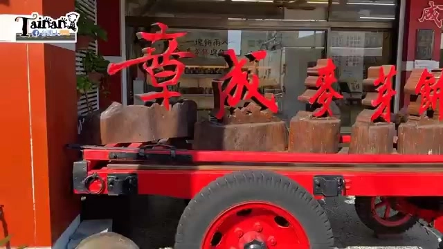 店門口擺放復古紅色木製推車，上頭掛著「章成麥芽餅」的大型立體招牌字樣