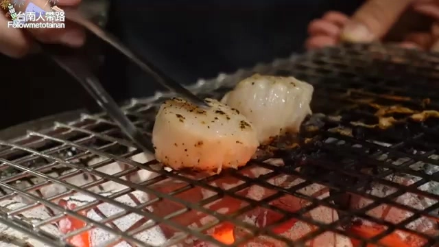 黑色石板上盛著兩塊烤干貝，表面微焦帶有炭烤香氣，佐以少許胡椒調味