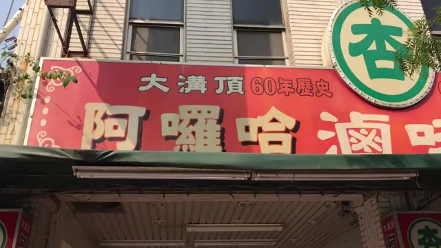 紅底金字招牌寫著「大溝頂60年歷史 阿囉哈滷味」,店門口懸掛綠色圓形品牌標誌