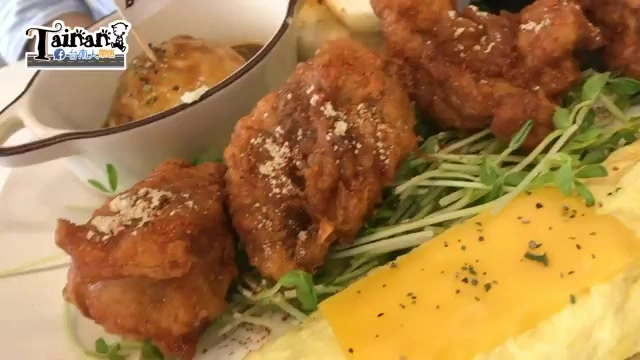 盤中盛著多塊金黃酥脆的炸雞塊，佐以芽菜與起司片，撒上香料粉末
