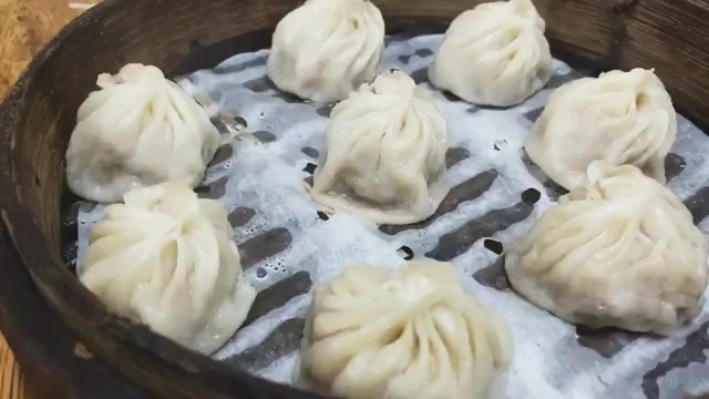 竹製蒸籠裡整齊排列著多顆小籠包,皮薄透亮,摺子清晰可見