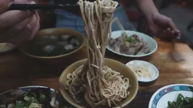 筷子夾起裹滿麻醬的麵條高高提起,色澤濃郁油亮,一旁配著滷味小菜