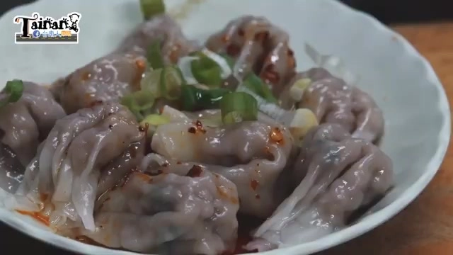 紅油抄手盛盤,淋上辣油並撒上蔥花,餃子形狀飽滿肉餡外露