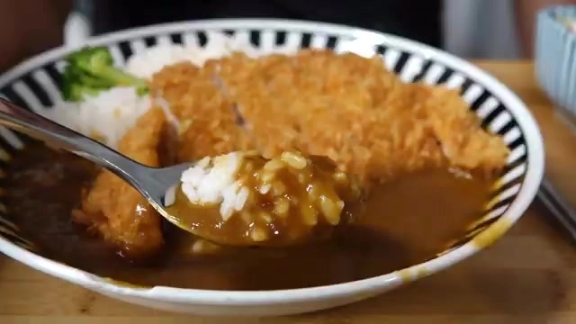 炸豬排咖哩特寫，湯匙舀起沾滿咖哩醬汁的白飯，豬排外酥內嫩切面清晰