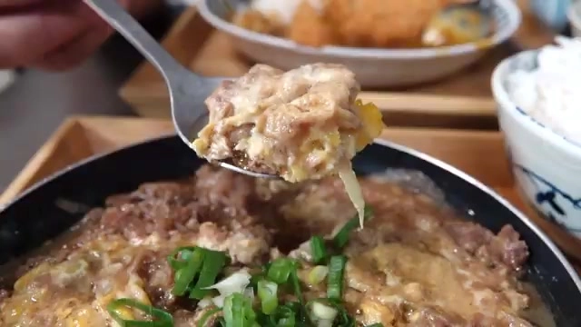 湯匙舀起牛肉與蛋液交融的牛丼配料，鍋中撒滿蔥花，色澤誘人