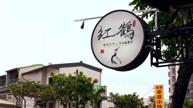 紅鶴牛肉麵招牌,寫著「眷村三代・牛肉麵專賣」,圓形招牌搭配仙鶴圖案