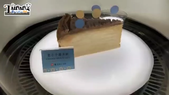 透明展示櫃中的巧克力千層蛋糕切片，標籤上寫著中英文品名與價格