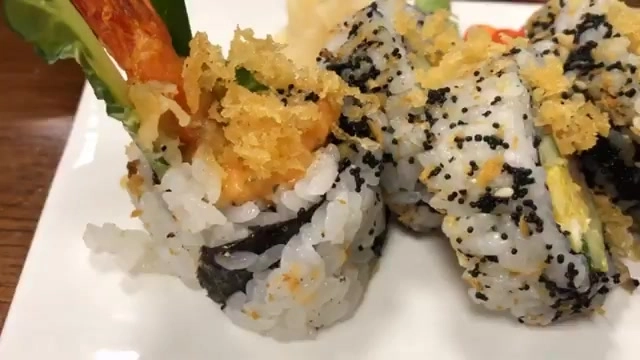 白色瓷盤盛著炸蝦壽司與海苔卷,米飯上撒著黑芝麻與酥脆配料