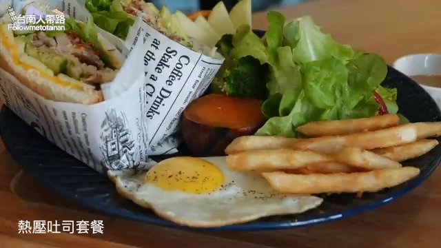 深藍色瓷盤盛著熱壓吐司套餐，附半熟太陽蛋、金黃薯條與生菜沙拉