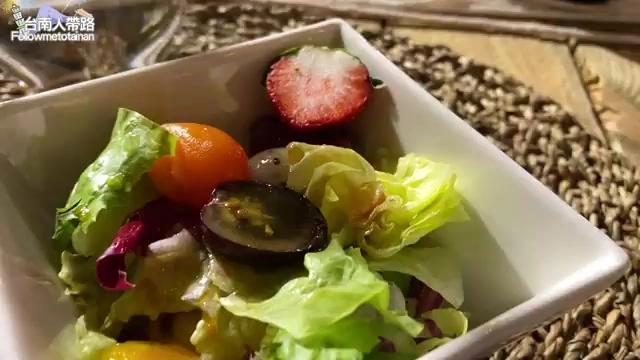 方形白盤中盛著生菜沙拉,點綴著草莓、小番茄與葡萄,色彩繽紛