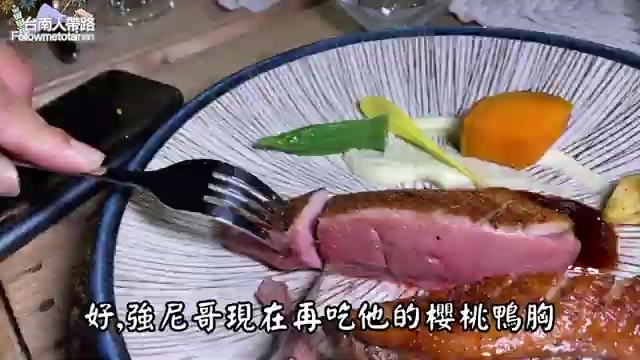 用叉子夾起的鴨胸肉片,切面呈現粉紅色澤,搭配蔬菜與醬汁擺盤精緻