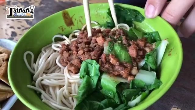 綠色碗中盛著陽春麵,筷子夾起肉燥與青菜,麵條清晰可見