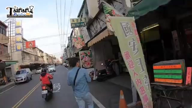 街道景象中可見一旁綠色招牌上寫著「國安街」路名，行人與機車往來
