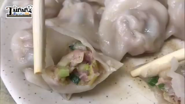 筷子夾起剖開的水餃,可見內餡包裹著肉丁與翠綠蔥花