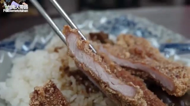 夾起的炸排骨切面，肉質粉嫩帶著肉汁，外層裹粉酥脆，鋪在白飯上
