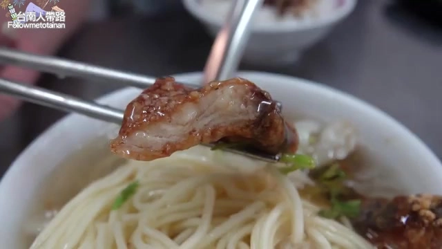 筷子夾起的魚肉塊搭配麵條，浸在湯汁中，色澤醬紅油亮