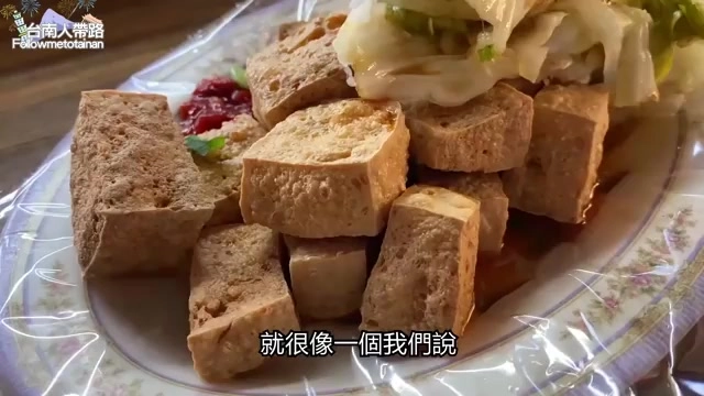 白色瓷盤中盛著切塊的炸臭豆腐，搭配新鮮泡菜與醬料點綴