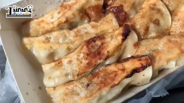煎餃裝在紙盒裡，外皮煎得金黃焦香，餡料隱約可見