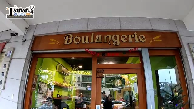 店面招牌寫著「Boulangerie」，暖黃燈光下可見玻璃展示櫃與門口顧客