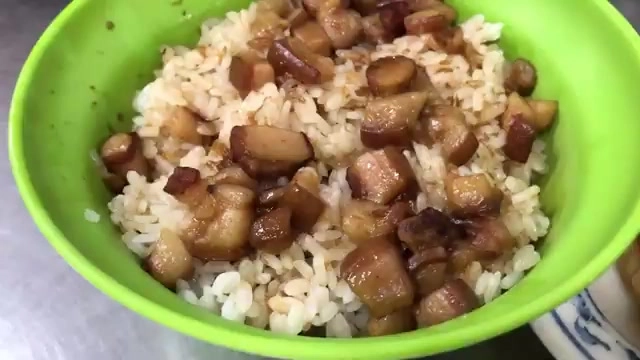綠色碗中盛著肉燥飯,深色滷肉塊均勻鋪滿米飯,油亮誘人