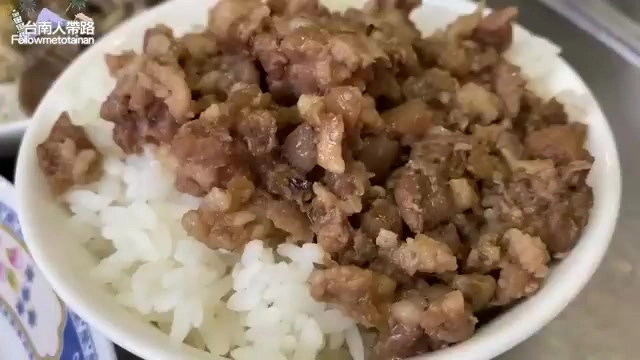 特寫拍攝白飯上鋪滿油亮的滷肉燥，顆粒分明香氣四溢