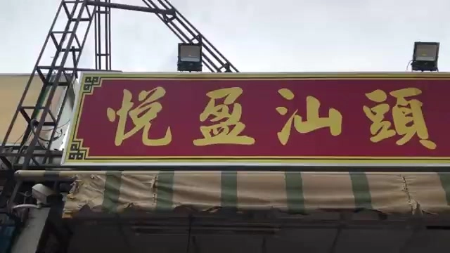 紅底金字招牌上寫著「悅盈汕頭」，搭配傳統邊框裝飾與條紋遮陽棚