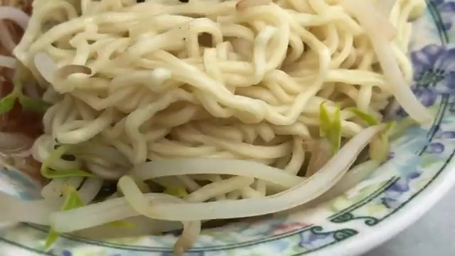 白色瓷碗盛著Q彈的黃色意麵，搭配豆芽菜與蔥花點綴