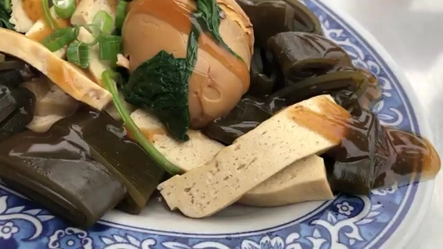 白色花紋瓷盤盛著滷豆干、滷海帶與滷蛋，淋著深色滷汁