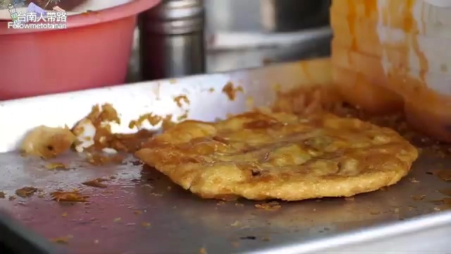 鐵板上剛煎好的蔥油餅,表面焦黃帶著油亮光澤,邊緣微焦