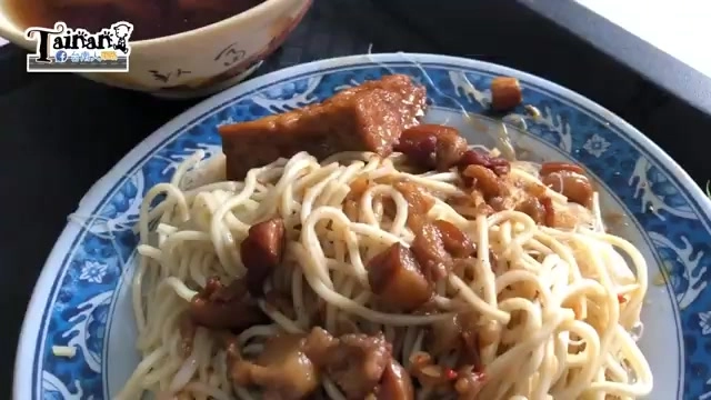 白色盤子盛著拌炒麵條，搭配深色滷肉丁，色澤油亮誘人