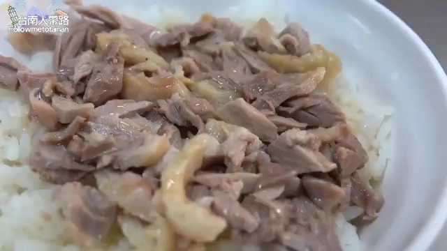 白飯上鋪滿撕碎的鴨肉，用筷子夾起，肉質油亮泛著光澤