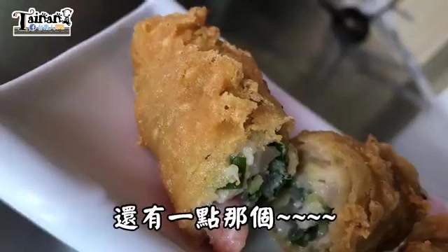 炸蝦捲剖半特寫，外皮金黃酥脆，內餡可見完整蝦仁與翠綠蔬菜餡料，字幕寫著「還有一點那個～～～～」