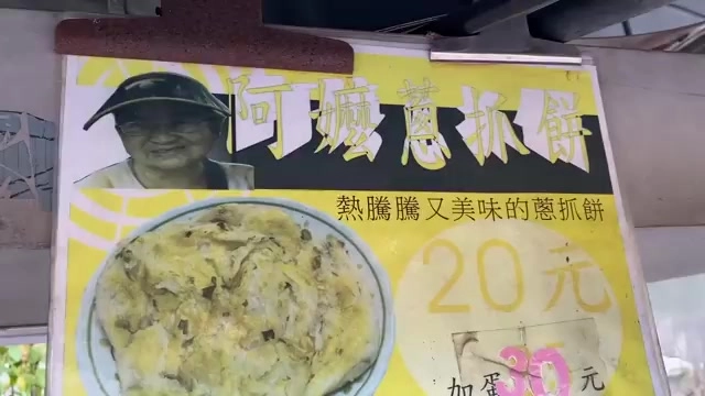 黃色手寫招牌寫著「阿嬤蔥抓餅」，標示熱騰騰又美味的蔥抓餅20元、加蛋30元，一旁附有老闆娘照片