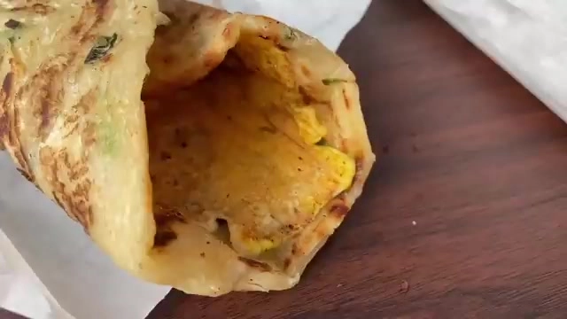 剖開的蔥抓餅露出裡面的煎蛋內餡，餅皮煎得金黃焦香，摺層分明