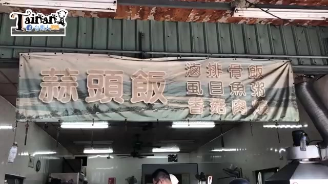 店家招牌，白底紅字寫著「蒜頭飯」，兩側標示滷排骨飯、虱目魚粥、香菇肉羹等品項，店內可見用餐顧客
