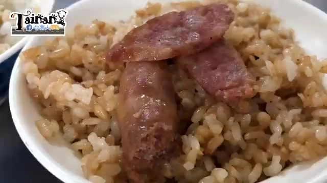 白色瓷碗盛著蒜頭飯，上頭放著兩片切好的香腸，米飯呈現油亮色澤