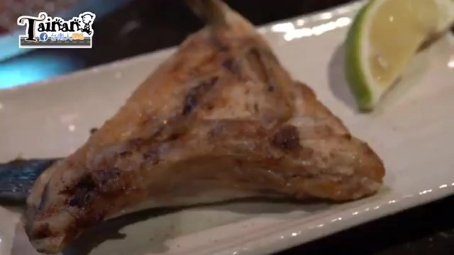 白色長盤盛著烤魚下巴，表皮焦香帶著烤紋，旁邊擺著一片檸檬角