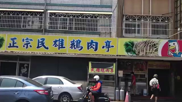 店面招牌黃底藍字寫著「正宗民雄鵝肉亭」，騎樓下停放機車與汽車，路人往來