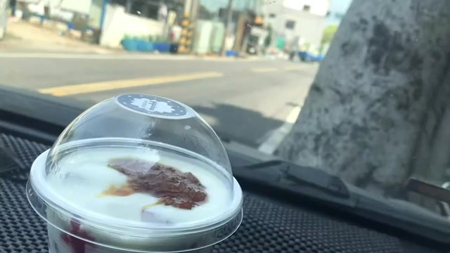 透明塑膠杯裝著白色優格，上面點綴著紅色果醬，杯身有品牌貼紙標籤