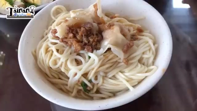 白色瓷碗盛著餛飩乾麵,麵條上鋪著肉燥與餛飩,撒上香菜點綴