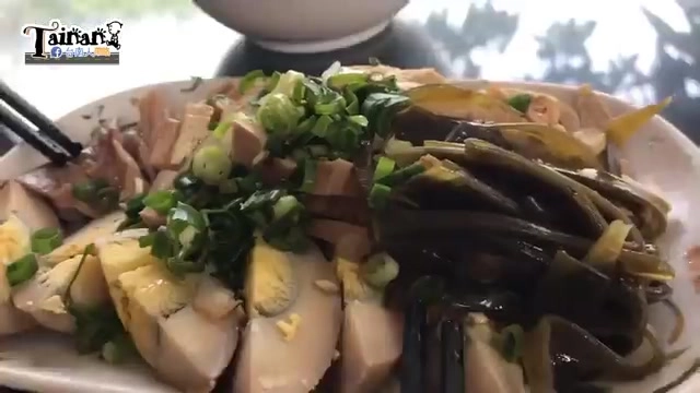 白色圓盤盛著滷味拼盤,滷蛋切片、海帶與豆干等配料撒上蔥花
