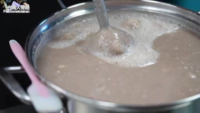 不鏽鋼鍋裡正在熬煮芋頭泥，質地綿密冒著細緻泡沫，一旁放著粉紅色攪拌棒