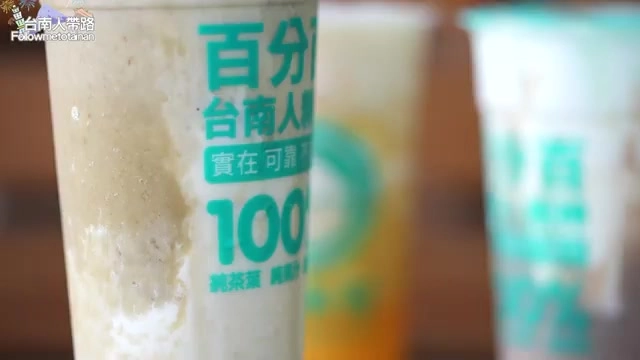 特寫飲料杯上印著「百分百台南人精神、實在可靠」字樣的芋頭牛奶飲品，質地濃稠