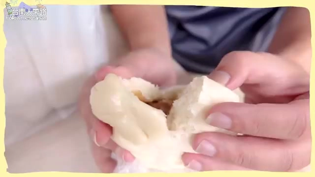 雙手撕開的白色包子,內餡露出深褐色醬汁與肉餡,熱氣蒸騰