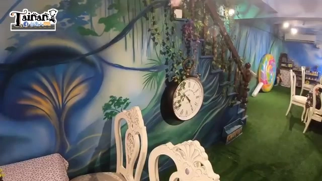 餐廳內部裝潢以森林為主題，牆上彩繪藤蔓與大型時鐘裝飾，搭配白色復古椅子與綠色地毯，氛圍夢幻