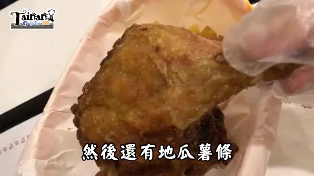 白色紙盒中盛著一隻金黃酥脆的炸雞腿,旁邊露出橘色地瓜薯條的一角