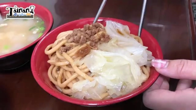 紅色瓷碗中的焢肉乾麵,麵條上鋪滿滷肉燥與燙高麗菜,一旁擺著清湯