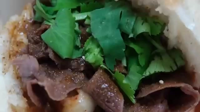 肉夾饃剖面特寫,露出切片羊肉與大量香菜,餅皮呈現金黃色澤
